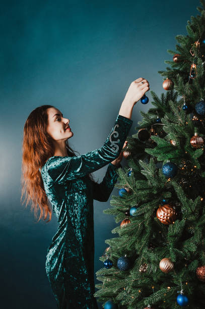 istock attractive smiling woman decorating Christmas tree 1399445476
