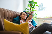 Happy young woman using mobile phone on sofa