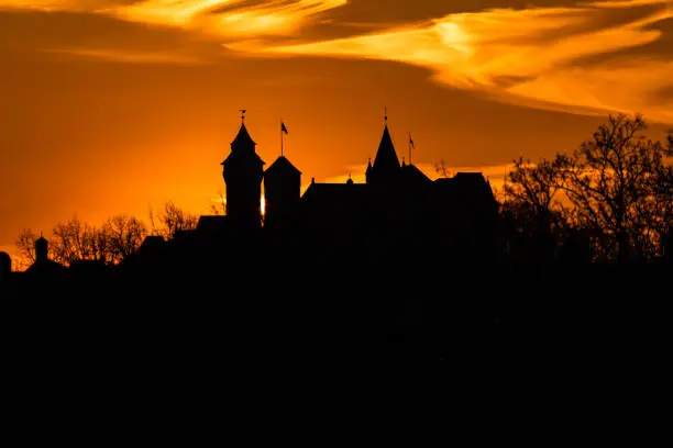 The silhouette of Nuremberg Castle shortly after sunset against the orange evening sky.