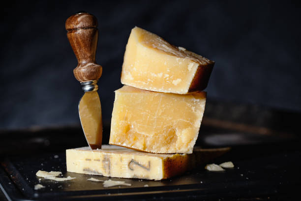 Parmesan cheese on wooden board Expensive parmesan cheese with knife on wooden board. Closeup grana padano stock pictures, royalty-free photos & images