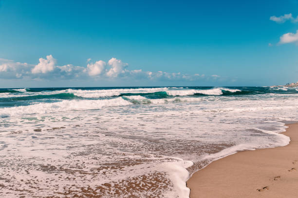 istock Footprints in sand on the ocean beach, blue sky, white clouds, yellow sand, turquoise waves 1399450048