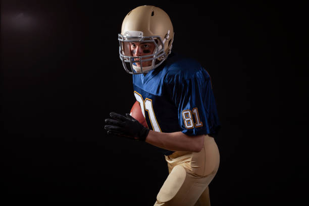 istock Young football player in running action on a dark background 1399451275