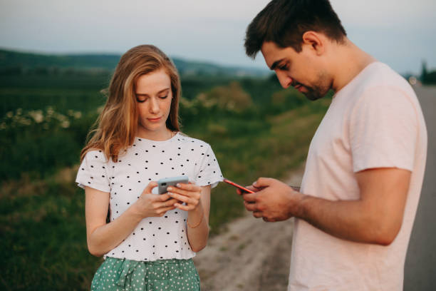 Caucasian looking into the smart phones, download photos taken from the country road. Mobile communication. Caucasian looking into the smart phones, download photos taken from the country road. Mobile communication. no signal stock pictures, royalty-free photos & images