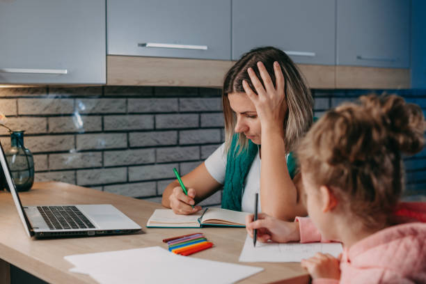 istock Mother using laptop to help her daughter at homework seated at table in kitchen. Homeschooling. 1399470040