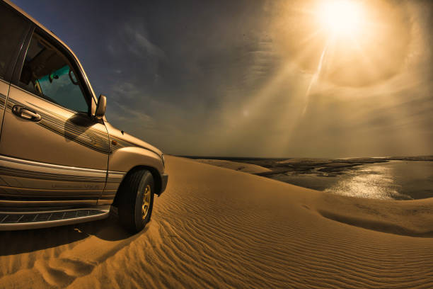 Doha, Qatar - January 28 2010 : riding in the desert with a 4x4 wheel drive car standing on a sand dune with view of the Persian gulf and bright sun