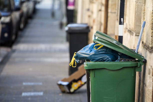 Garbage bins and containers full, overflowing, with bags falling on ground in residential area of Bordeaux, France, in a green container. "n"nPicture of garbage containers in Bordeaux, France, overflowing with garbage bags falling on the ground. overflowing dumpster stock pictures, royalty-free photos & images