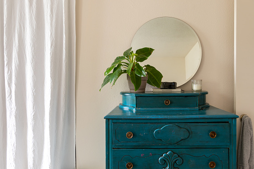 Dresser with a plant and a round mirror. Common things in and around the house