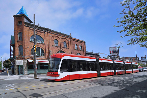 Toronto, Ontario, Canada - May 25, 2022:  Streetcars or trams running on tracks embedded in the road are a common form of public transit in the older parts of downtown Toronto, with modern new multi-car trains.