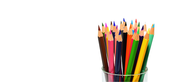 Several colored pencils in a crayon glass holder isolated with copy space on white background