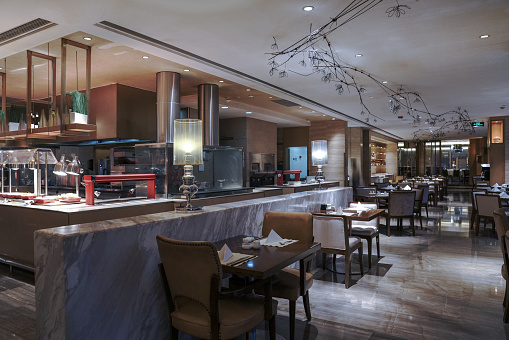 Modern design style upscale restaurant, tables have been set, elegant lighting.