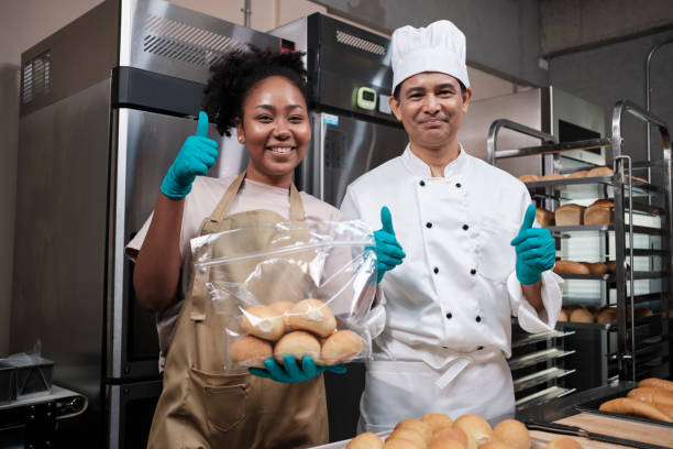 istock Two professional chefs in uniforms look at camera, cheerful with bread products. 1399486784