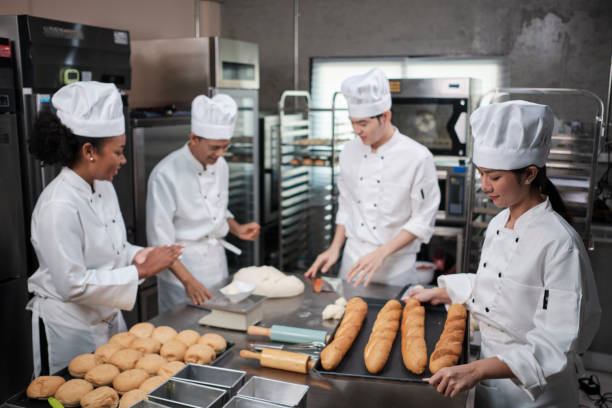 istock Chefs team in uniforms prepare to bake bread and pastry in stainless kitchen. 1399486809