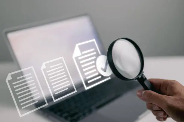 Documents and magnifying glass. Confirmed or approved document on laptop computer.