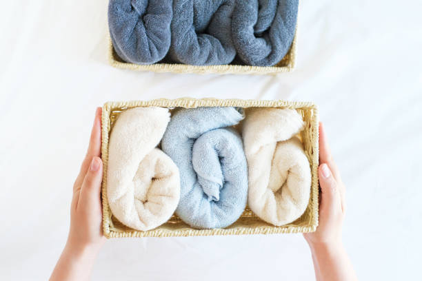 istock Female hands hold wicker box with rolled towels inside on a white background top view. 1399490134