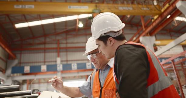 Industrial engineer or technician have skills and expertise. Wearing safety uniform and hard hat, Explaining about product, production process of machine and maintenance system at metal steel manufacture. Worker working in heavy industrial. ingeniero industrial o técnico tiene habilidades y experiencia. uso de uniforme de seguridad y casco, explicación sobre el producto, el proceso de producción de la máquina y el sistema de mantenimiento en la fabricación de acero metálico. trabajador
