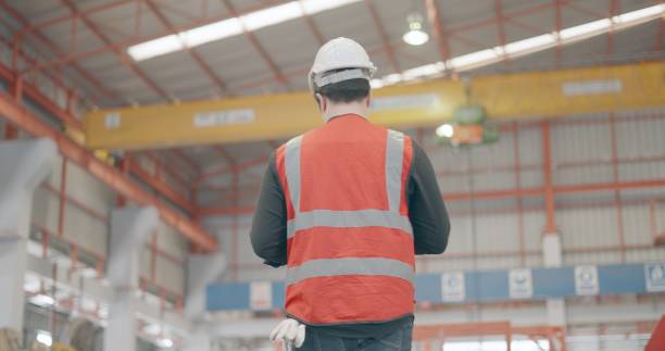 istock Rear view. Professional industrial engineer wear personal protective equipment, using tablet to planning, monitor production line process of assembly part, production control of machine in manufacturing factory. Worker or foreman in metal work in factory. 1399497204