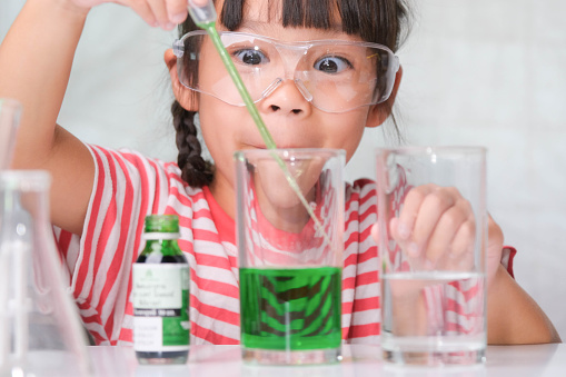 Children are learning and doing science experiments in the classroom. Little girl playing science experiment for home schooling. Easy and fun science experiments for kids at home.