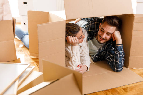 istock Couple lying on front, inside a cardboard box, looking and smiling at each other 1399499820