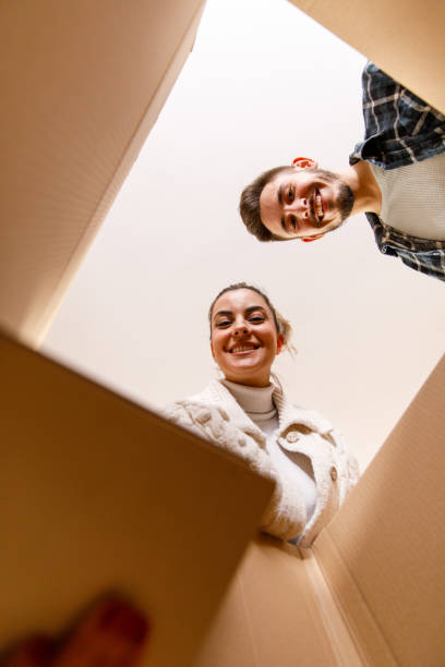 istock Couple smiling at camera when packing a box and moving home 1399499835