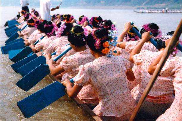 In the 1990s,Dragon boat racing in the Water Splashing Festival in Xishuangbanna,a group of women racing in a dragon boat In China it is called Water Splashing Festival, also known as Songkran festival in Thailand.The main aboriginal people in Xishuangbanna, Yunnan province, China are called Dai Tribe, aiso is Thai  Ethnicity.The festival lasts for several days, with dragon-boat races, water splashing, traditional songs and dances, fairs and more.Film photo in April 1995,Xishuangbanna,Southern Yunnan xishuangbanna stock pictures, royalty-free photos & images