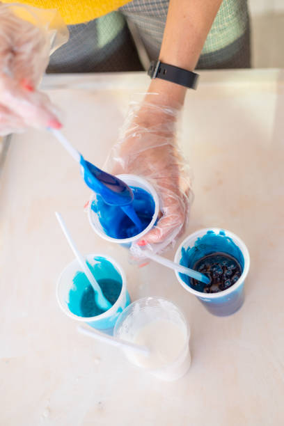 istock Epoxy resin, different blue color in cup for casting stabilizing wood, abstract art. Process of making accessory from resin.Mixing colorful of resin chemical in plastic cup 1399501432