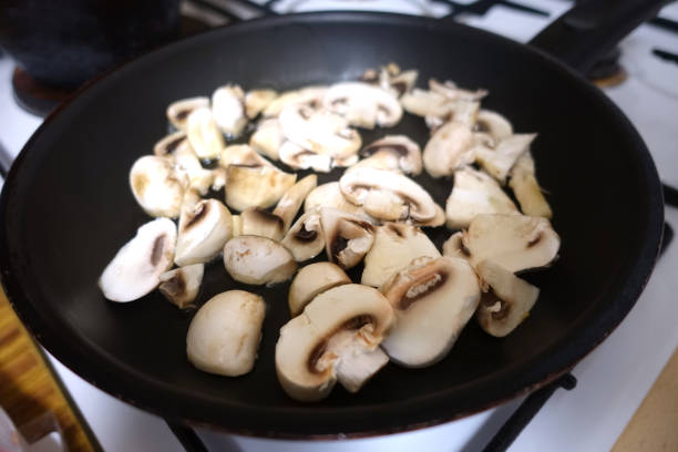 Button mushrooms being cooked in a frying pan