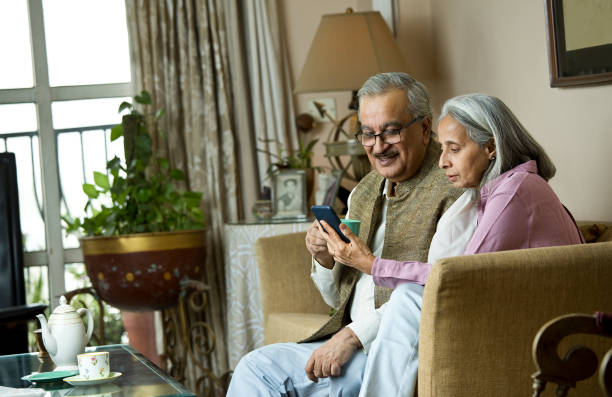 istock Old couple having fun while drinking coffee and watching media content using mobile phone at home 1399509555