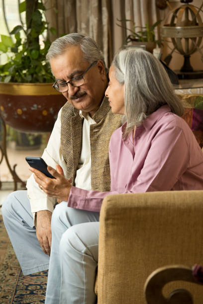 istock Elderly couple spending leisure time while using mobile phone at home 1399512103