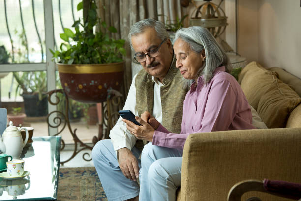 istock Old couple having fun while drinking coffee and watching media content using mobile phone at home 1399512118
