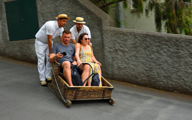 Funchal, Madeira, Portugal  -  June 26, 2019:  Funchal  Madeira  couple having downhill  basket ride.