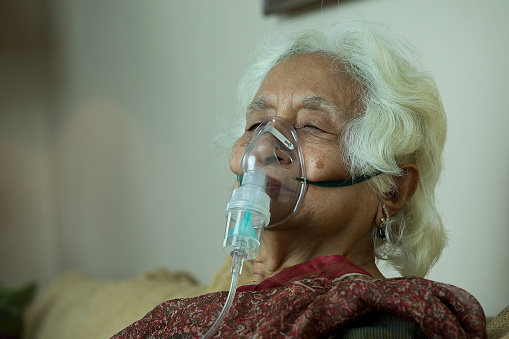 Senior woman with oxygen mask at home