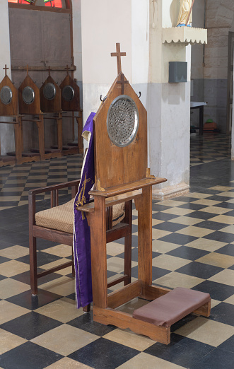 A confessional chair and kneeler bench inside a church in southern India.