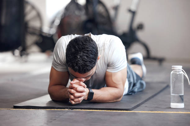 One exhausted young hispanic man taking a break while struggling to exercise in a gym. Muscular mixed race man looking tired, disappointed and ready to quit after intense training and challenging workout. Overtraining can lead to injury and muscle pain un joven hispano exhausto tomando un descanso mientras luchaba por hacer ejercicio en un gimnasio. hombre musculoso de raza mixta que parece cansado, decepcionado y listo para dejar de fumar después de un entrenamiento intenso y un entrenamiento desafiant
