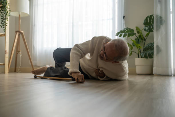 asiatischer älterer mann, der auf den boden fällt, während er mit einem walker zu hause spazieren geht. älterer älterer reifer großvater, der einen unfall hat, nachdem er nach der pensionierung im wohnzimmer im haus alleine physiotherapie gemacht hat - falling senior adult people one person stock-fotos und bilder