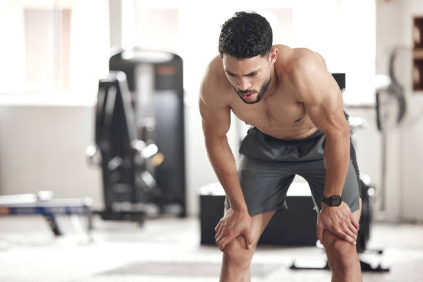 istock One exhausted young hispanic man taking a rest break to catch his breath while exercising in a gym. Fit sexy topless mixed race bodybuilder sweating after an intense training workout in a fitness centre 1399520840