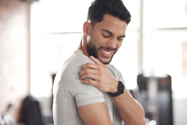 istock One young hispanic man holding his sore shoulder while exercising in a gym. Guy suffering with painful arm injury from fractured joint and inflamed muscles during workout. Struggling with stiff body cramps causing discomfort and strain 1399520944