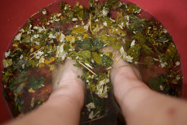 Woman bare feet in water with various leaves at home in bathroom.