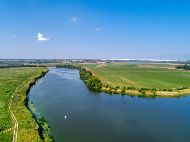 istock Large green field and trees near tranquil river in spring 1399521611