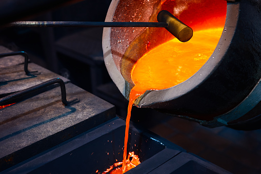 Pouring molten metal to molding system to produce castings in steel mill.