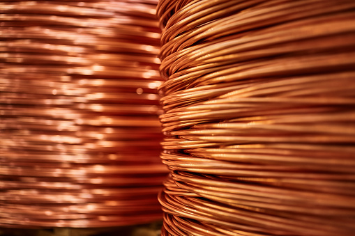 Large bobbin of thick orange copper wire in light spacious warehouse of contemporary equipment production plant extreme closeup