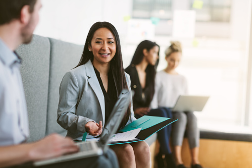 Multiracial young woman sits to discuss with work colleagues plans and ideas in modern coworking shared business office