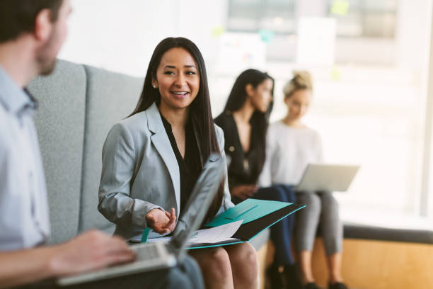Multiracial young woman sits to discuss with work colleagues plans and ideas in modern coworking shared business office stock photo