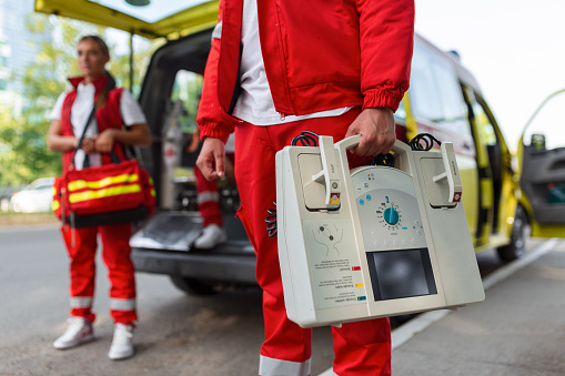 Hand of the doctor with defibrillator. Teams of the Emergency medical service are responding to an traffic accident.