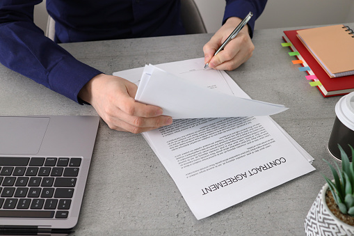 Businessman sitting at office desk signing a contract.