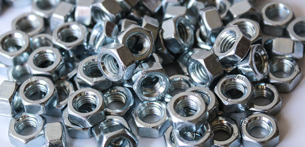 Pile of shiny metallic nuts in random arrangement. A closeup view.