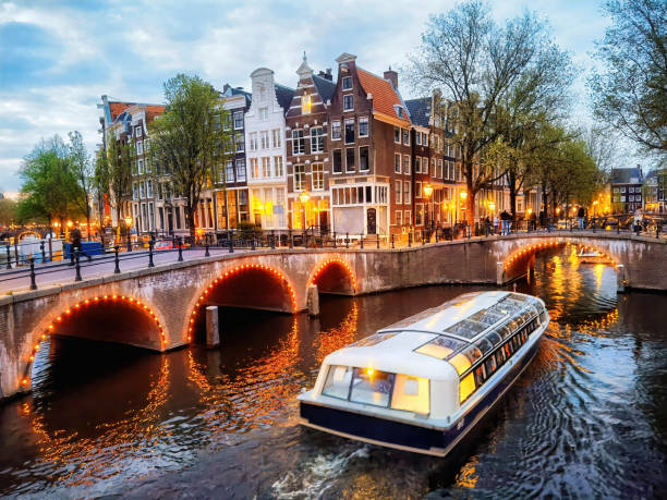 Amsterdam boat canal at dusk Evening time boat at the junction of the Leidsegracht and Keizersgracht canals on Amsterdam's historic canal ring. tourist boat on the canal of amsterdam the netherlands stock pictures, royalty-free photos & images