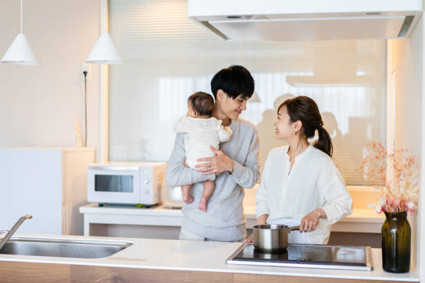 junge familien, die sich kinderbetreuung und hausarbeit teilen - two parent family indoors home interior domestic kitchen stock-fotos und bilder