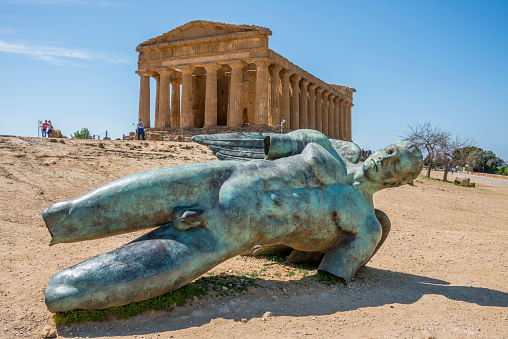 Agrigento, Sicily, Italy - March 24, 2017: Bronze sculpture of fallen Icarus in front of the Temple of Concordia in the Valley of the Temples