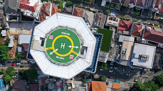 Top down view of helicopter landing pad on the roof of modern skyscraper in Jakarta city.