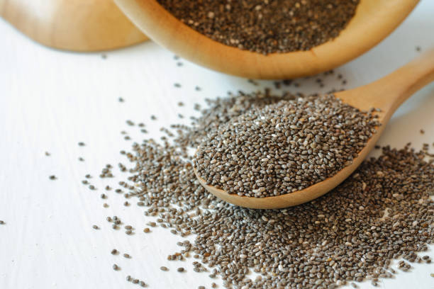 istock Chia seeds piled on a table and in a wooden spoon on a white background. 1399532308